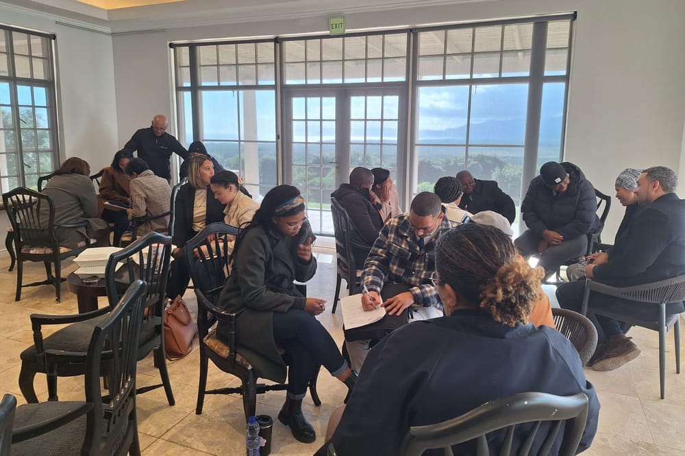 School management team members working in small groups, writing and talking, during a Dinaledi session